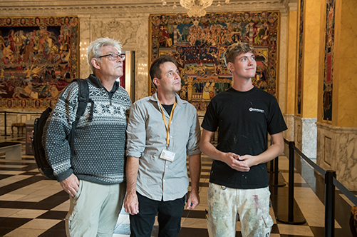 Malermester Martin Behrendt står mellem sin far Flemming Jensen og sønnen Tinus Behrendt. Tre generationer, der brænder for malerfaget og de gamle malerteknikker i Riddersalen på Christiansborg,  hvor de både har malet og sat gobeliner op.