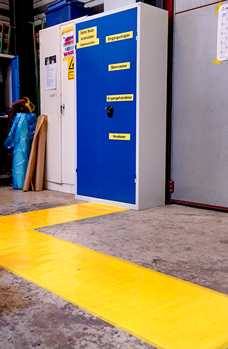 Nudging skal ikke nødvendigvis være pænt at se på. På DSB's værksted i Aarhus leder en fed, gul stribe på gulvet hen til et skab med værnemidler.